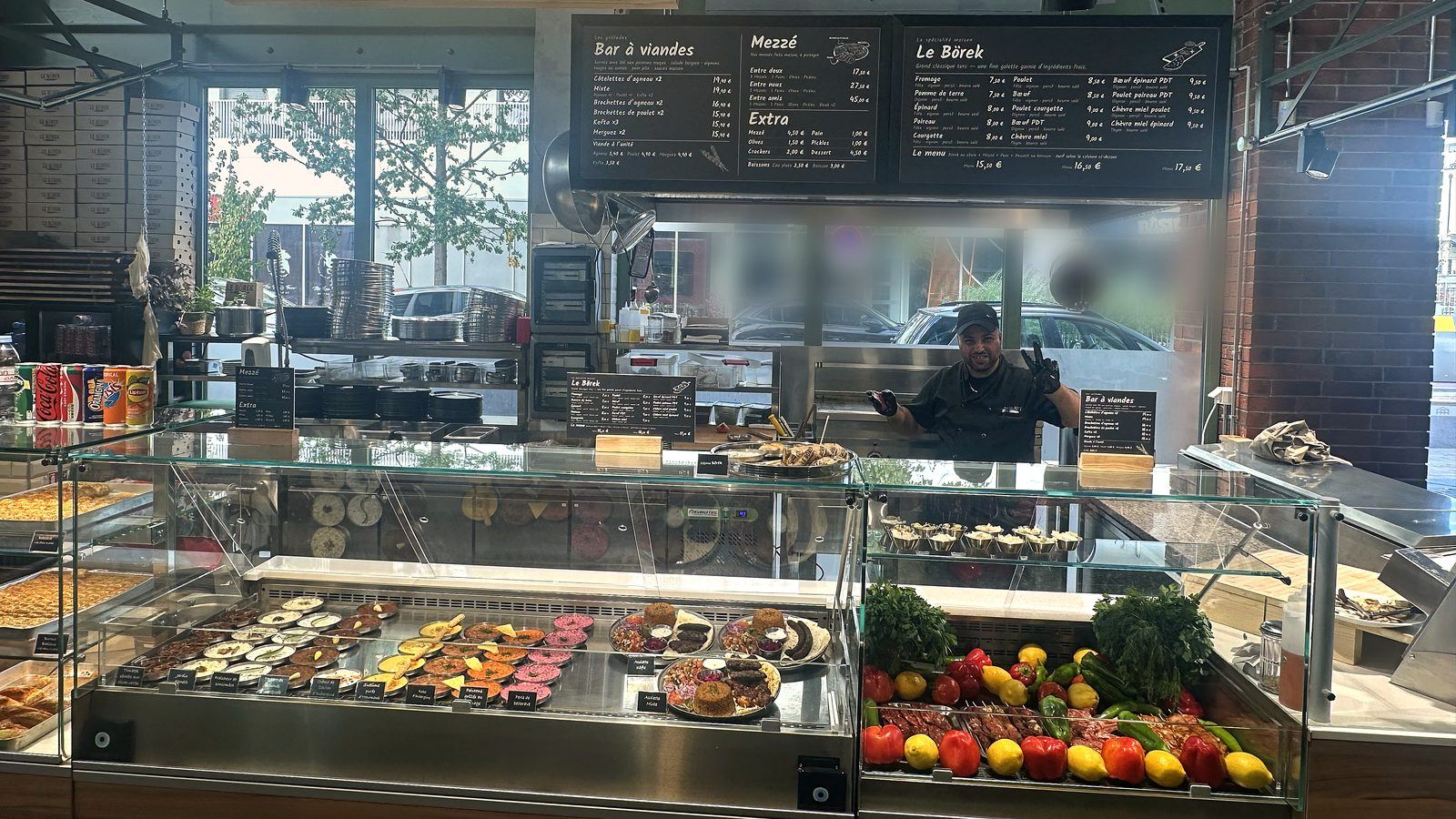 Le comptoir Börek & Co : la vitrine de mezzés, les brochettes et le cuisinier derrière le plan de travail